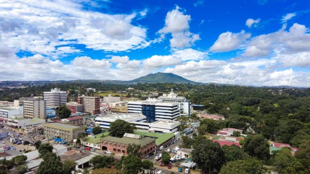 Aerial view of Blantyre city, Malawi, with Mount Soche in the background under a bright blue sky.